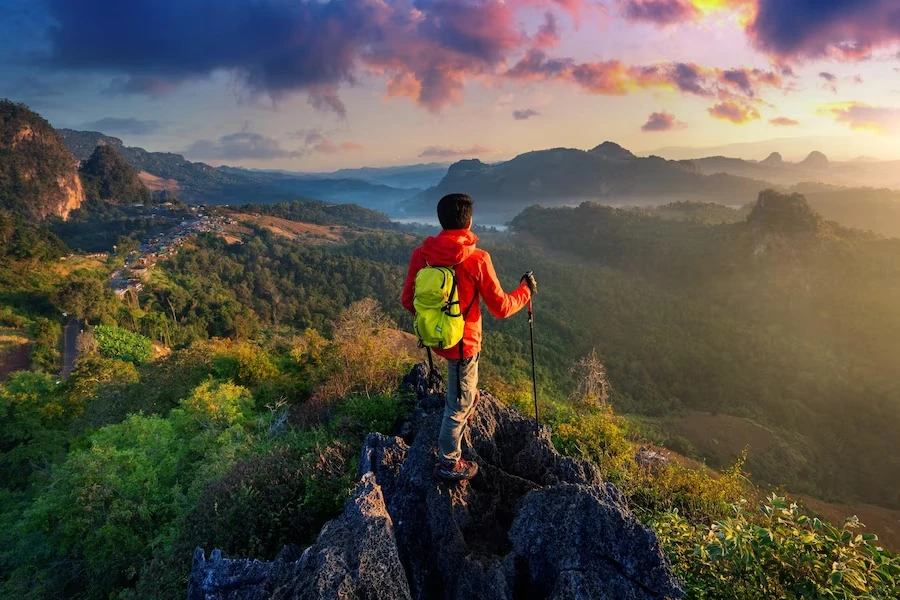Hiker on a mountain at sunset overlooking a valley.