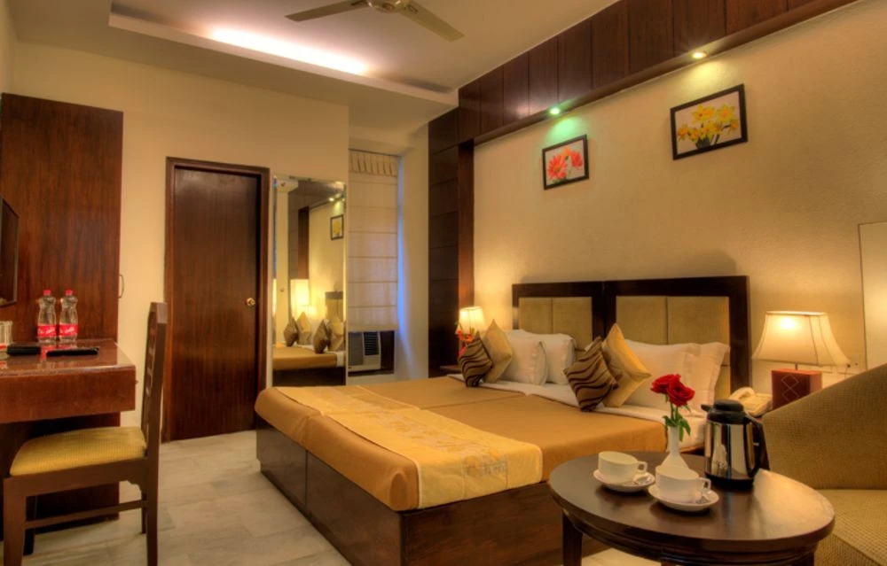 Cozy hotel room interior with a double bed, side tables, lamps, and art on the wall.