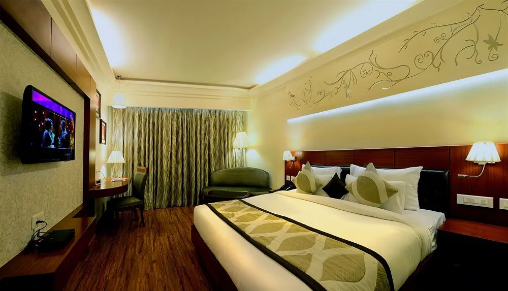 Elegant hotel room with a large bed, mounted TV, and artistic wall decor.