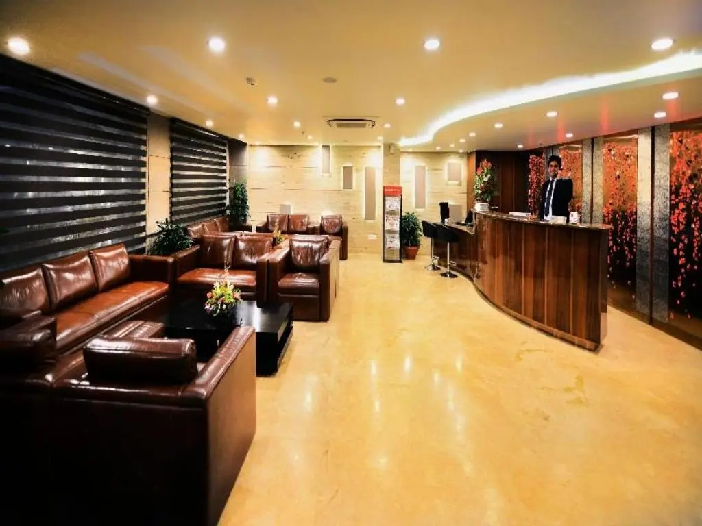 Modern hotel lobby with reception desk, leather sofas, and warm lighting.