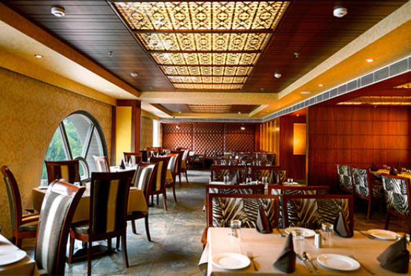 Elegant restaurant interior with decorative ceiling lighting and set tables.